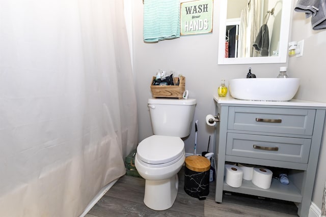 bathroom with vanity, wood finished floors, toilet, and curtained shower