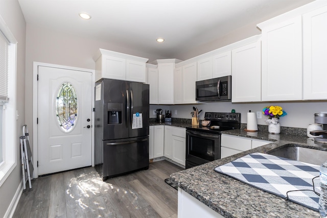 kitchen with wood finished floors, white cabinets, black appliances, dark stone countertops, and recessed lighting
