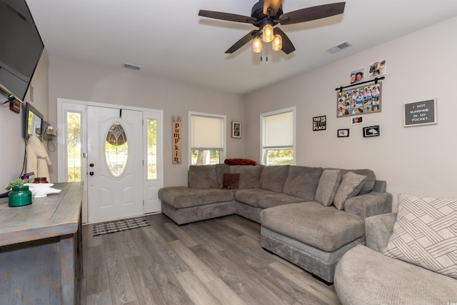 living area with a ceiling fan, visible vents, and wood finished floors