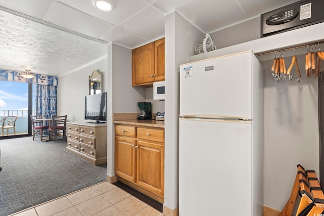 7100 N Ocean Blvd Unit 612, Myrtle Beach, SC 29572 - kitchen featuring freestanding refrigerator, light colored carpet, crown molding, light countertops, and light tile patterned floors