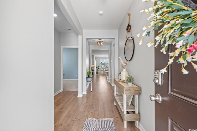 hall with visible vents, light wood-style flooring, and baseboards