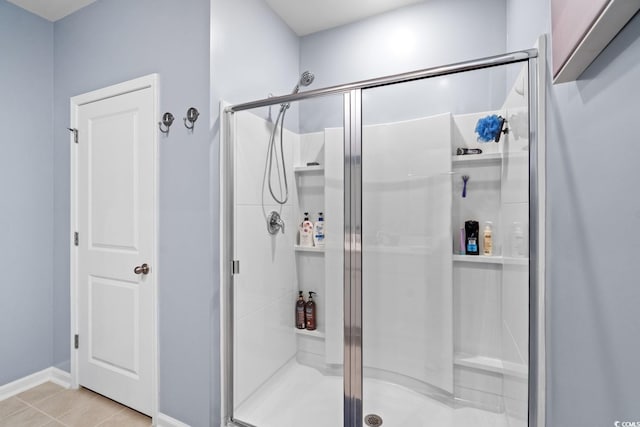 bathroom with tile patterned flooring, a stall shower, and baseboards