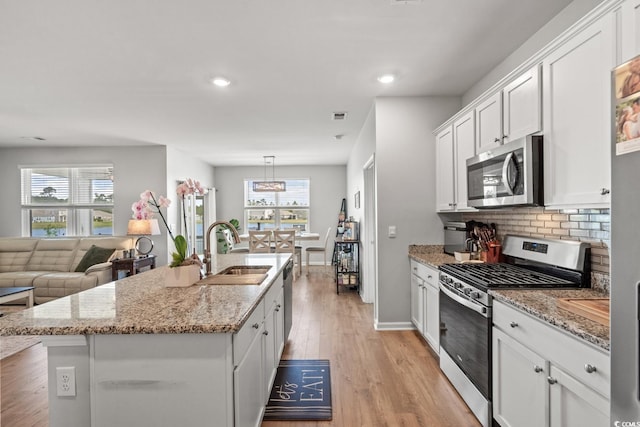 kitchen featuring a sink, white cabinets, stainless steel appliances, and a healthy amount of sunlight
