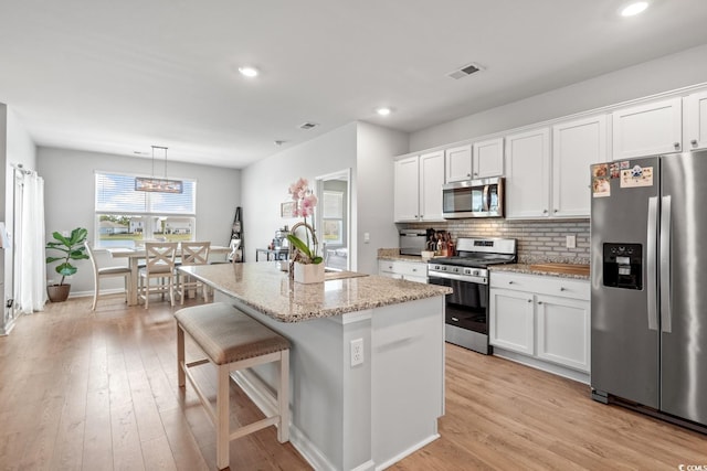 kitchen with a sink, white cabinets, stainless steel appliances, and decorative backsplash