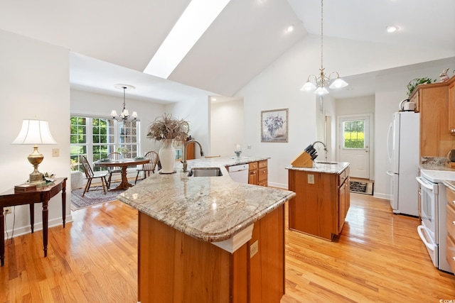 kitchen with a large island, a chandelier, white appliances, brown cabinets, and a sink