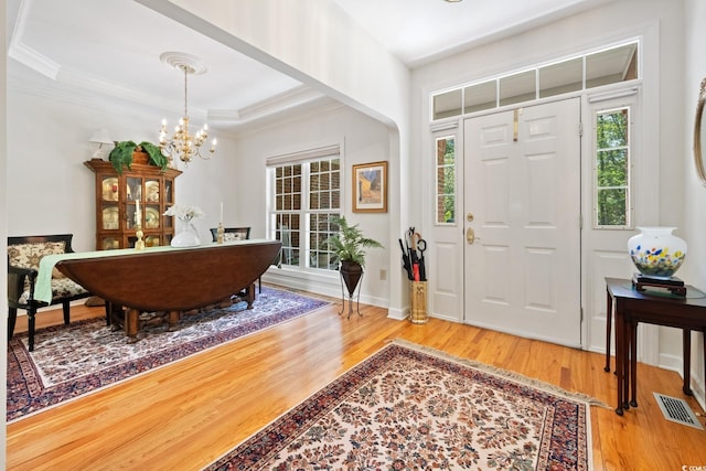 foyer featuring a chandelier, crown molding, and wood finished floors