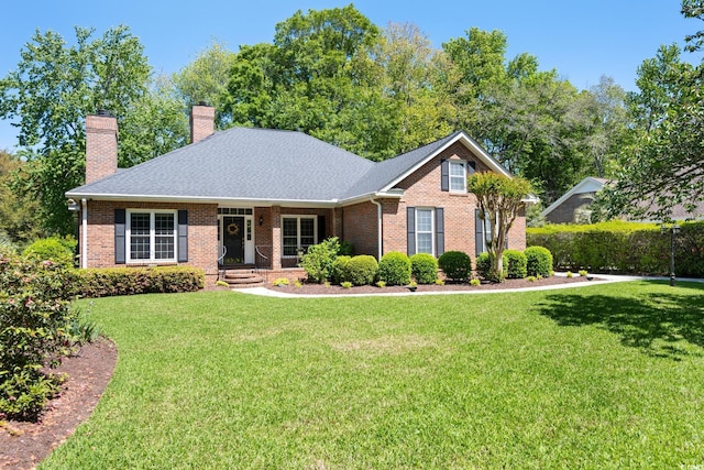 ranch-style home featuring a front yard, a shingled roof, brick siding, and a chimney