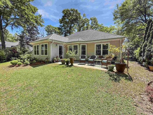 rear view of house featuring a yard, an outdoor hangout area, a patio, and a shingled roof