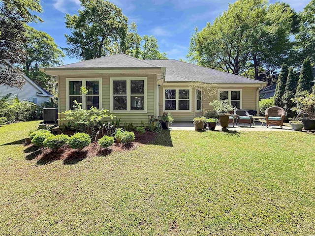 back of property featuring a shingled roof, a patio area, and a lawn