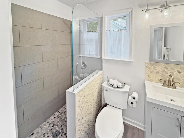 bathroom featuring toilet, vanity, decorative backsplash, and walk in shower