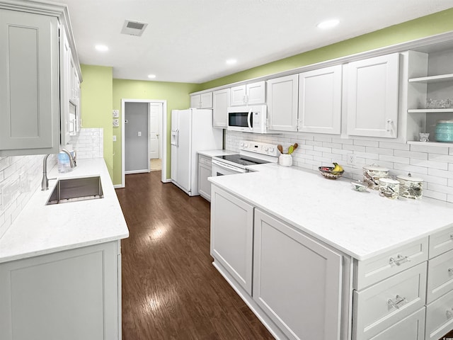kitchen featuring tasteful backsplash, visible vents, a sink, white appliances, and dark wood-type flooring