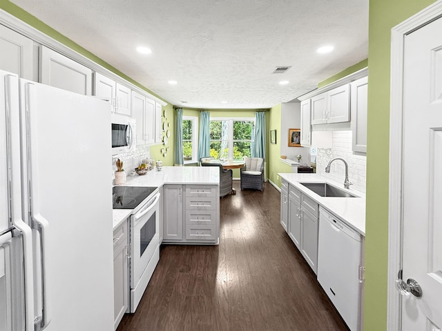 kitchen featuring recessed lighting, white appliances, light countertops, and a sink