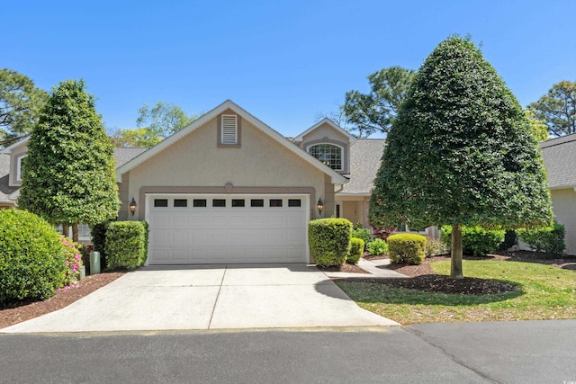 traditional-style home with concrete driveway, an attached garage, and stucco siding