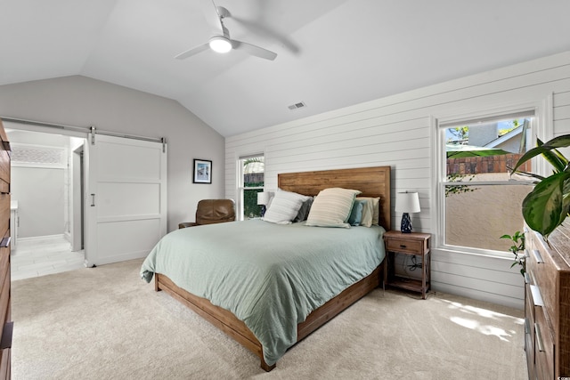 bedroom with light colored carpet, visible vents, a barn door, wood walls, and lofted ceiling