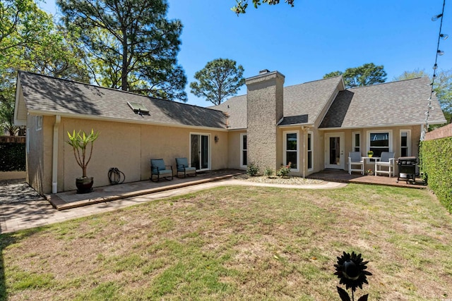 back of property featuring a yard, stucco siding, a chimney, and a patio area