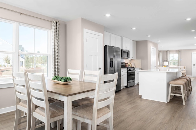 dining space with light wood-type flooring, baseboards, and recessed lighting