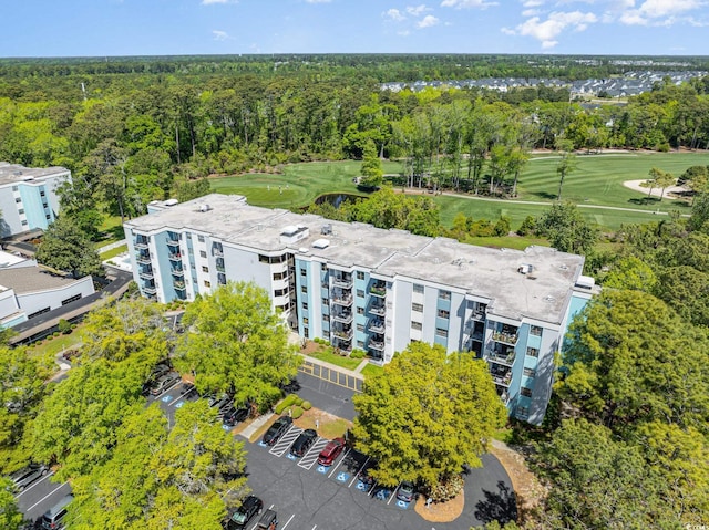 drone / aerial view of apartment complex / building, a forest, and a local golf course