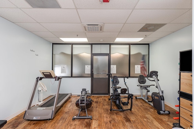exercise area featuring wood finished floors, baseboards, and a drop ceiling