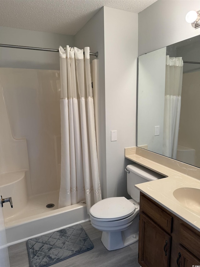 full bath with wood finished floors, a shower with shower curtain, toilet, a textured ceiling, and vanity