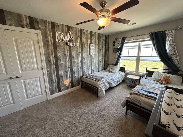 bedroom with wood walls, carpet floors, and ceiling fan