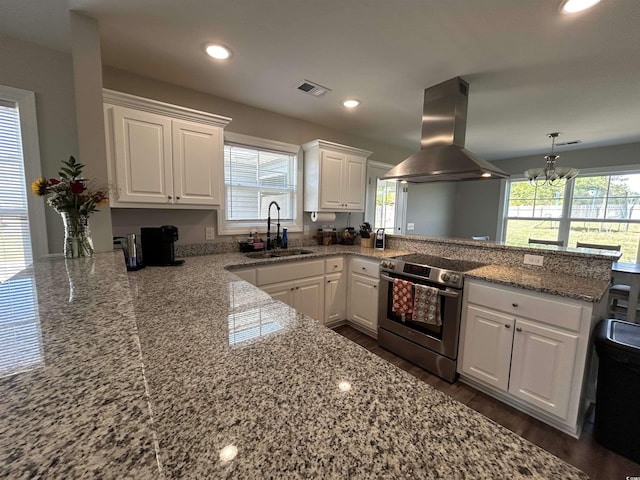 kitchen with island range hood, stainless steel electric range oven, a sink, a peninsula, and white cabinetry