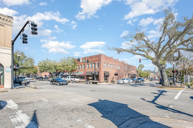 view of asphalt street featuring traffic lights, street lighting, curbs, sidewalks, and traffic signs