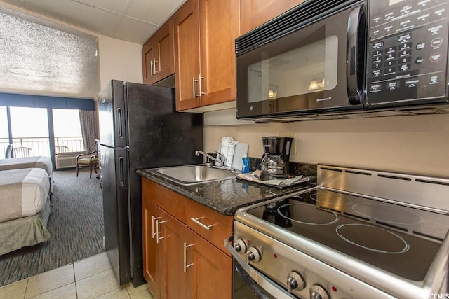 1200 N Ocean Blvd N Unit 905, Myrtle Beach, SC 29577 - kitchen featuring black appliances, brown cabinetry, light tile patterned flooring, open floor plan, and dark stone counters