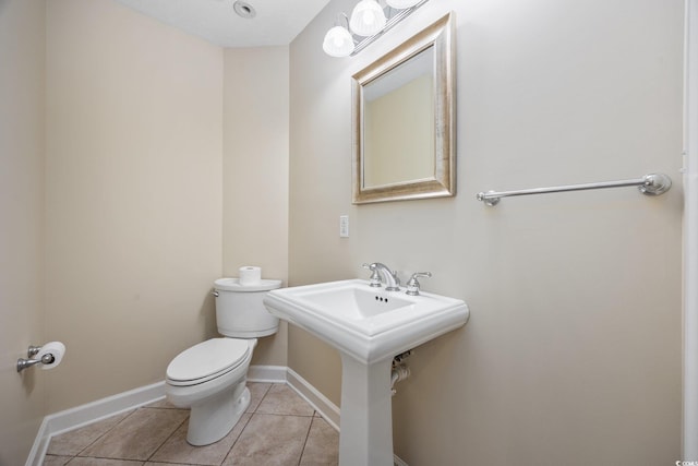 half bathroom featuring tile patterned floors, toilet, and baseboards