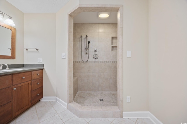 full bathroom featuring a walk in shower, tile patterned flooring, vanity, and baseboards