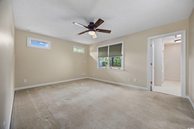 carpeted spare room featuring ceiling fan and baseboards