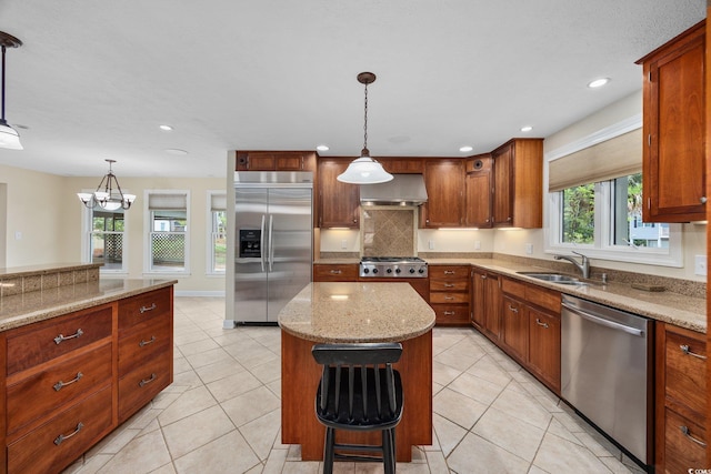 kitchen featuring stainless steel appliances, a sink, a center island, wall chimney exhaust hood, and backsplash