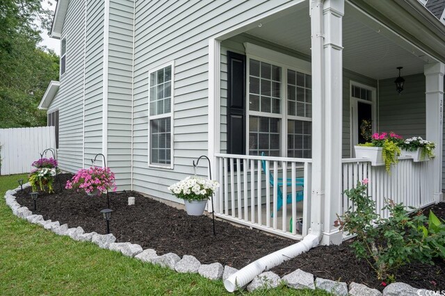 view of side of property featuring a porch and fence