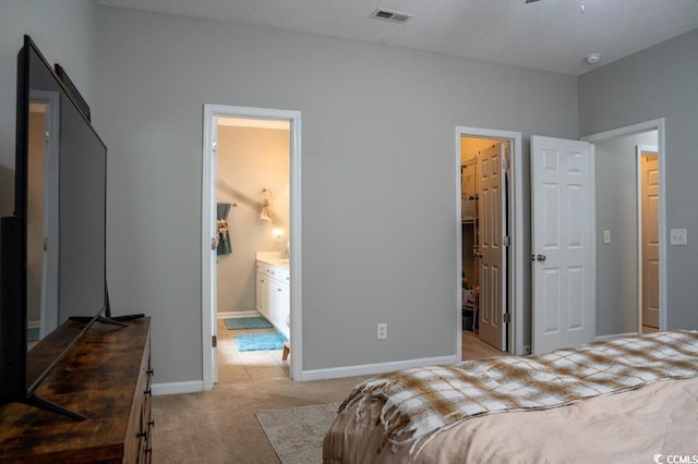 bedroom with light carpet, baseboards, and ensuite bath
