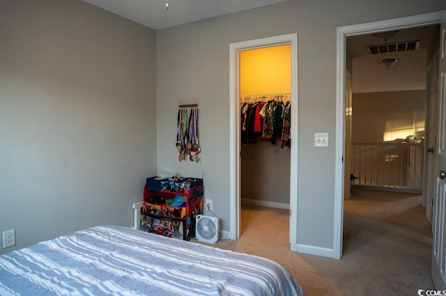 carpeted bedroom featuring a spacious closet, baseboards, and a closet