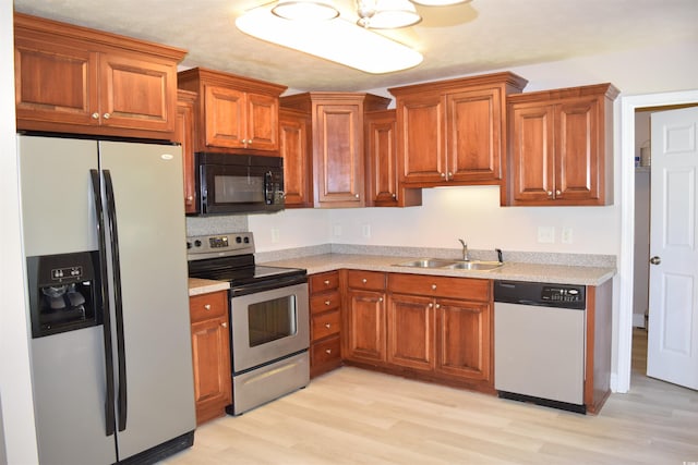 kitchen featuring stainless steel appliances, light wood-style floors, light countertops, and a sink