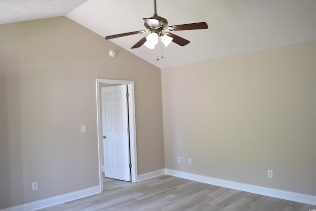 spare room featuring lofted ceiling, ceiling fan, light wood finished floors, and baseboards