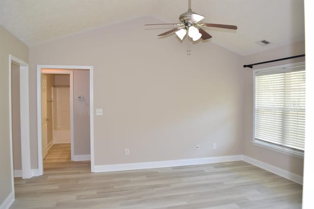 empty room with visible vents, ceiling fan, light wood finished floors, and vaulted ceiling