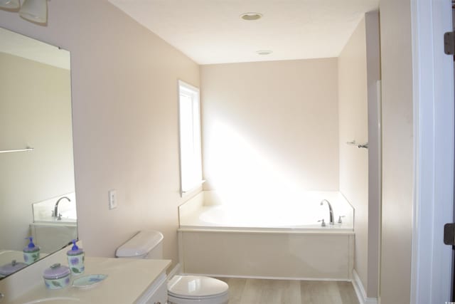 full bathroom featuring toilet, vanity, a garden tub, and wood finished floors