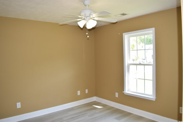 empty room featuring baseboards, visible vents, a ceiling fan, and light wood-style floors
