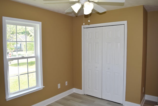 unfurnished bedroom featuring ceiling fan, baseboards, light wood finished floors, and a closet