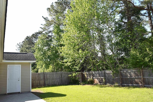 view of yard featuring a storage shed, a fenced backyard, and an outdoor structure