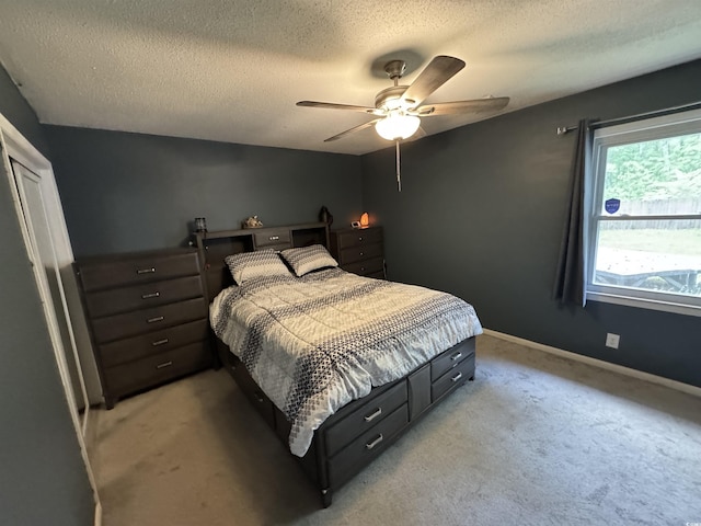bedroom with light colored carpet, baseboards, a ceiling fan, and a textured ceiling