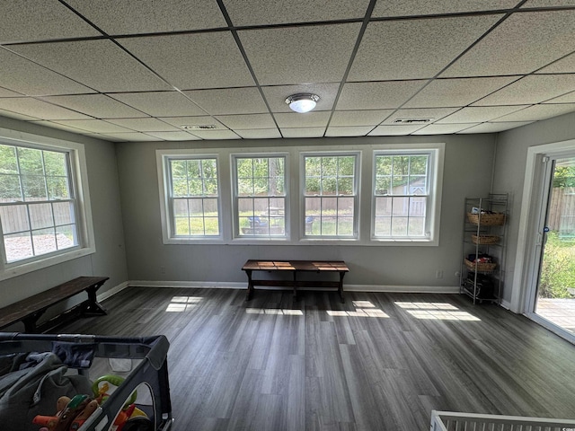 interior space with baseboards, a drop ceiling, and a wealth of natural light