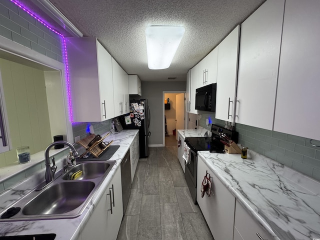 kitchen featuring a sink, black microwave, range with electric cooktop, backsplash, and white cabinetry