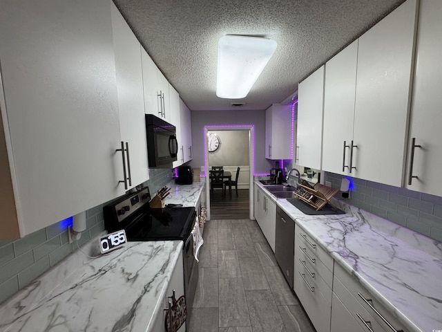 kitchen with a textured ceiling, decorative backsplash, stainless steel appliances, and a sink