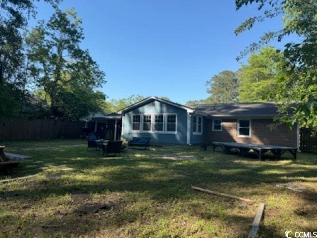 rear view of house with a yard and fence