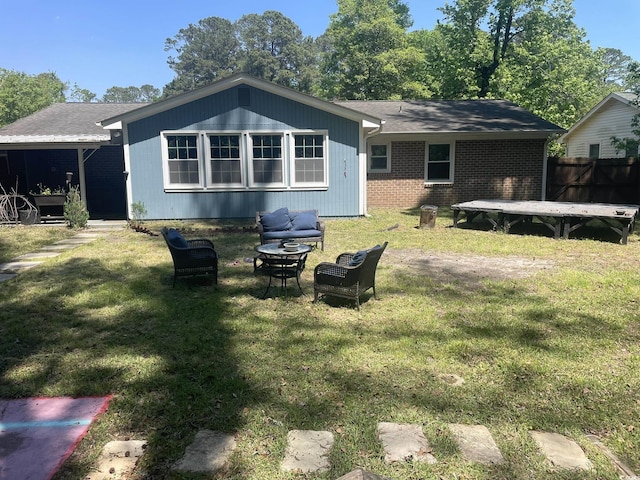 rear view of house with a fire pit, brick siding, fence, and a yard