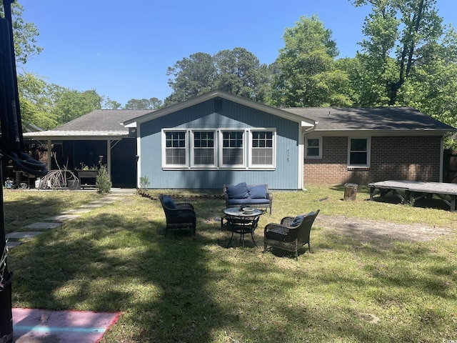 back of property with a lawn, brick siding, roof with shingles, and an outdoor fire pit