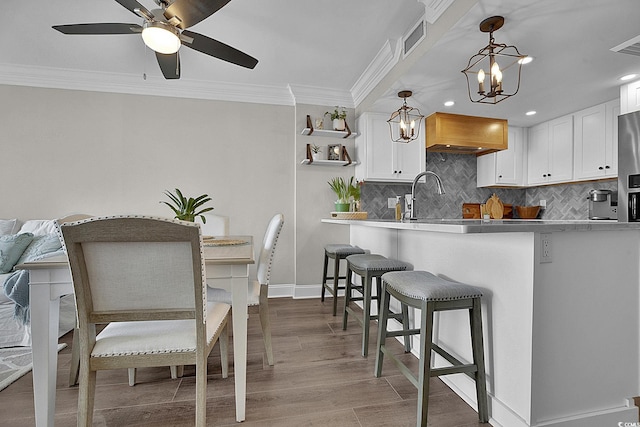 kitchen with tasteful backsplash, ornamental molding, white cabinetry, and visible vents