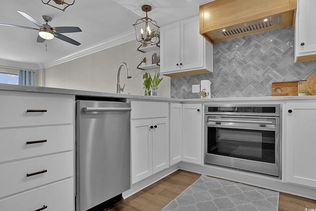 kitchen with ceiling fan, tasteful backsplash, custom exhaust hood, ornamental molding, and stainless steel appliances